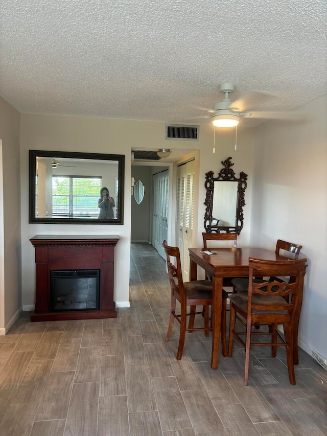 dining room featuring hardwood / wood-style floors, ceiling fan, and a textured ceiling