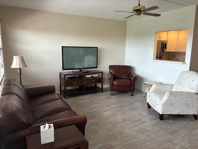 living room featuring a textured ceiling, light hardwood / wood-style flooring, and ceiling fan