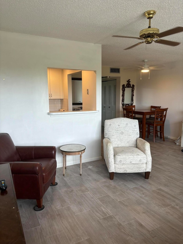 sitting room featuring ceiling fan, hardwood / wood-style flooring, and a textured ceiling