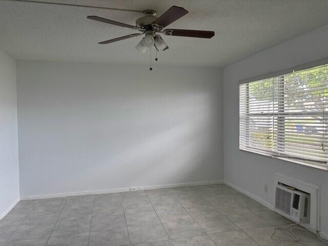 spare room with an AC wall unit and ceiling fan