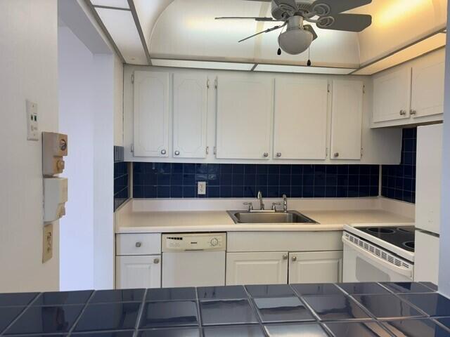 kitchen featuring sink, white appliances, white cabinets, and backsplash