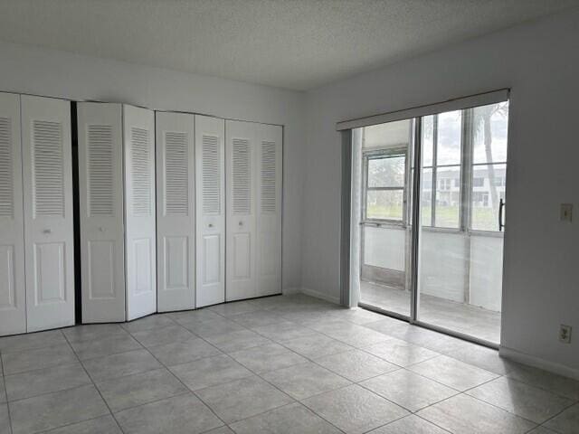 unfurnished bedroom with two closets, a textured ceiling, and light tile patterned floors