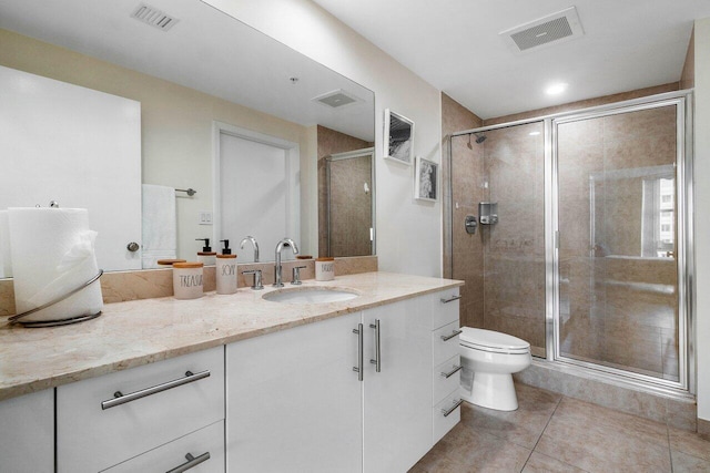 bathroom with toilet, vanity, tile patterned floors, and a shower with shower door