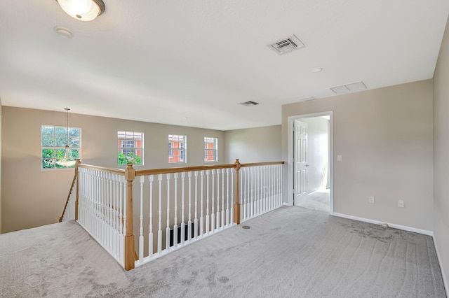 carpeted spare room featuring a chandelier