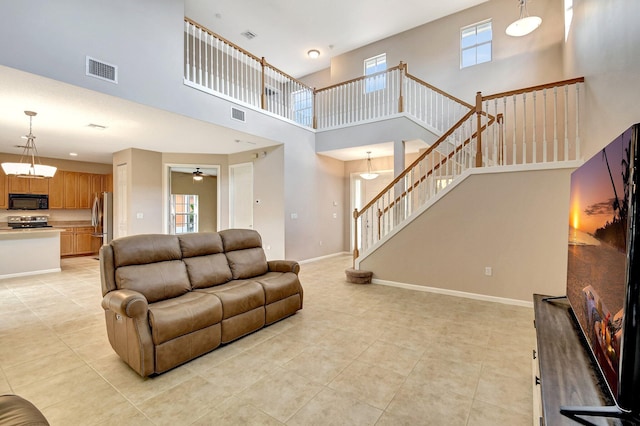 living room featuring a healthy amount of sunlight, a towering ceiling, and ceiling fan with notable chandelier