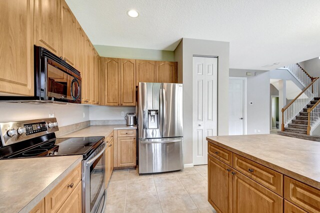 kitchen with a textured ceiling, light tile patterned floors, and appliances with stainless steel finishes