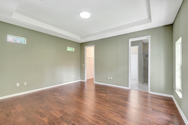 empty room with a raised ceiling and wood-type flooring