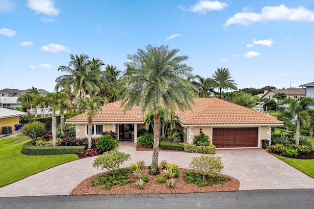 mediterranean / spanish-style home featuring cooling unit, a front yard, and a garage