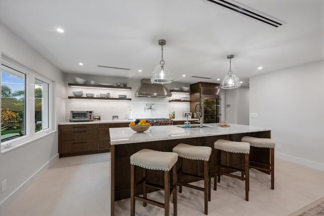 kitchen featuring a breakfast bar area, hanging light fixtures, exhaust hood, and sink