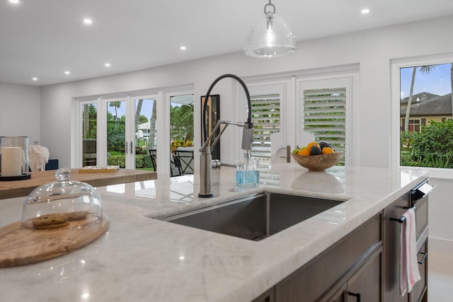 kitchen featuring french doors, sink, light stone countertops, and hanging light fixtures