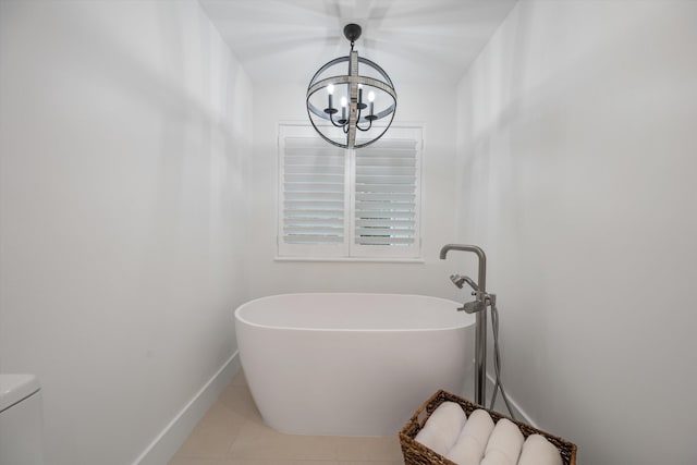 bathroom with a tub to relax in, toilet, tile patterned floors, and a chandelier