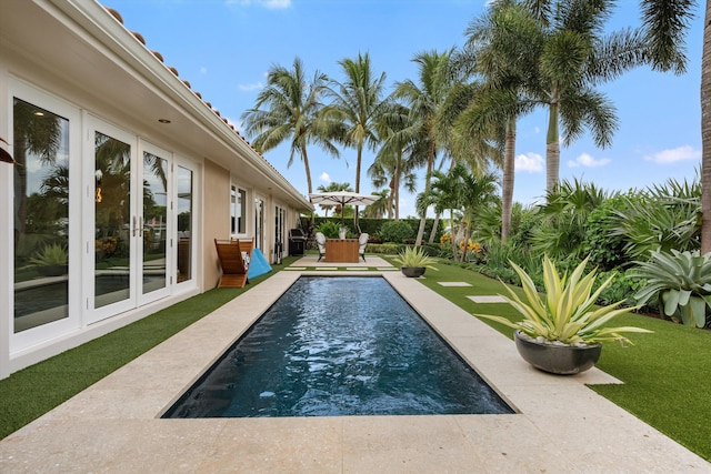 view of pool featuring a patio area, a lawn, and french doors