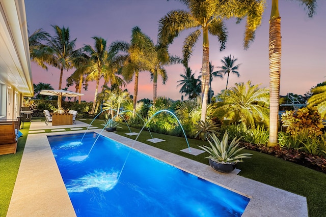 pool at dusk featuring a patio area and pool water feature