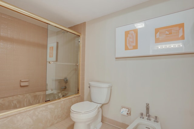 bathroom featuring tile patterned floors, toilet, bath / shower combo with glass door, and a bidet