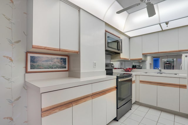 kitchen featuring appliances with stainless steel finishes, ceiling fan, sink, light tile patterned floors, and white cabinets