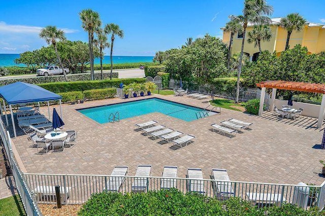 view of pool with a pergola, a patio area, and a water view