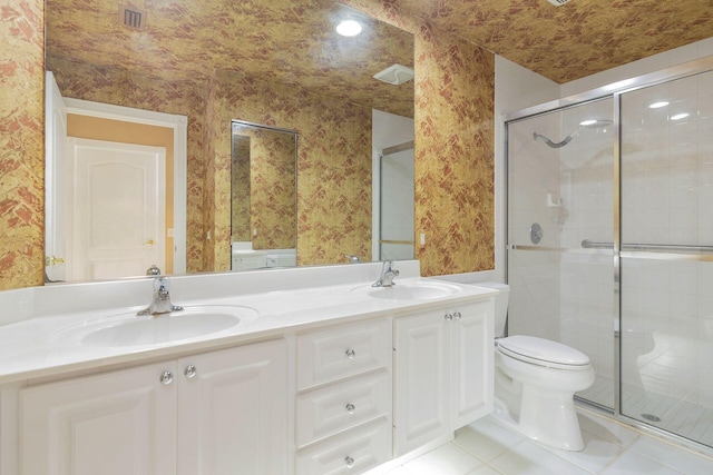 bathroom featuring tile patterned flooring, vanity, toilet, and a shower with shower door