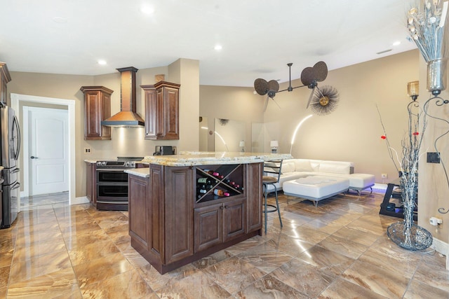 kitchen featuring a kitchen breakfast bar, vaulted ceiling, stainless steel appliances, a center island, and wall chimney range hood