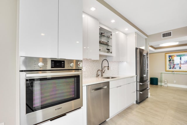 kitchen with white cabinetry, appliances with stainless steel finishes, sink, and backsplash