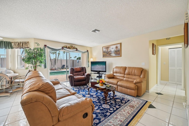 living room featuring light tile patterned floors, a textured ceiling, and a wealth of natural light