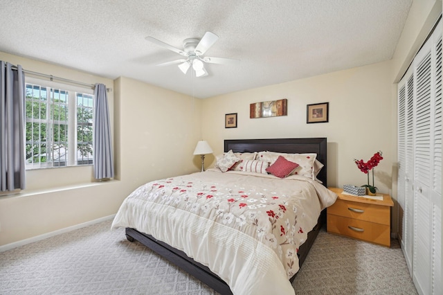 carpeted bedroom featuring ceiling fan, a textured ceiling, and a closet