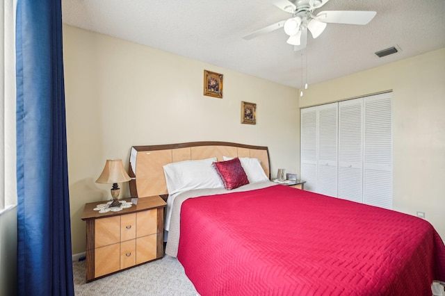 carpeted bedroom with ceiling fan, a textured ceiling, and a closet