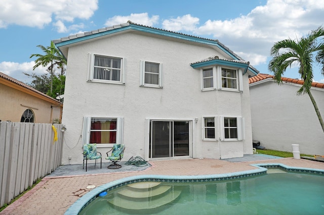 rear view of house featuring a fenced in pool and a patio