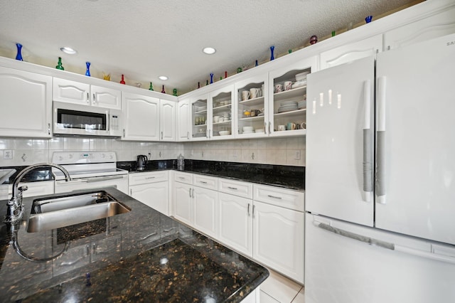 kitchen with backsplash, dark stone counters, white appliances, sink, and white cabinets