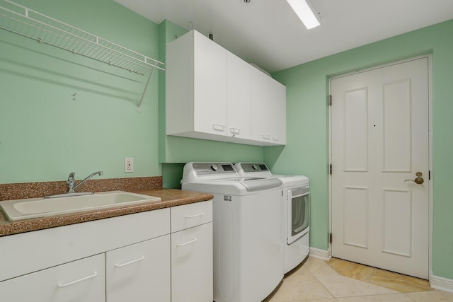 laundry room with washer and clothes dryer, light tile patterned floors, a sink, baseboards, and cabinet space