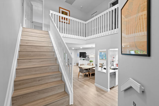 stairs featuring a towering ceiling and hardwood / wood-style flooring