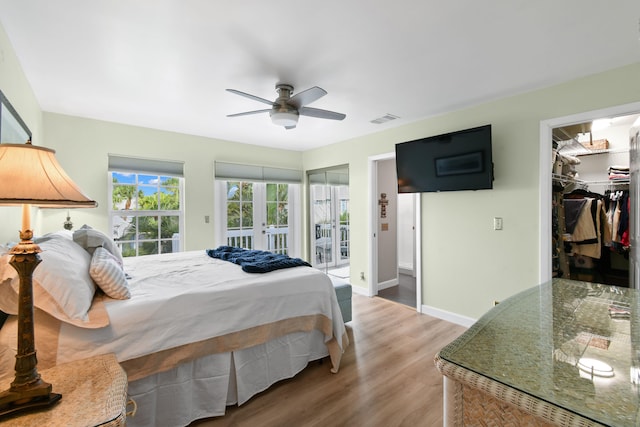 bedroom featuring a closet, hardwood / wood-style flooring, access to exterior, a spacious closet, and ceiling fan