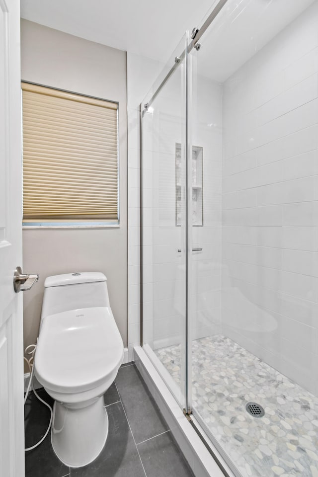 bathroom with tile patterned flooring, toilet, and an enclosed shower