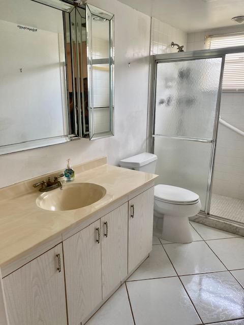 bathroom featuring walk in shower, vanity, toilet, and tile patterned floors