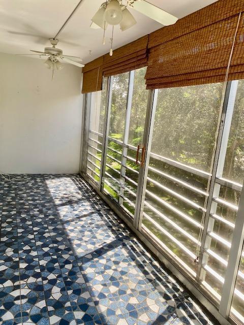 unfurnished sunroom featuring ceiling fan