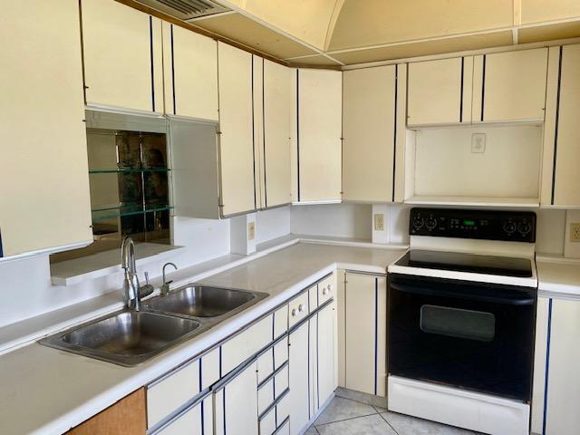 kitchen with white electric range oven, light tile patterned floors, and sink