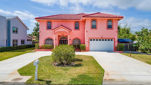 mediterranean / spanish home featuring a garage and a front lawn