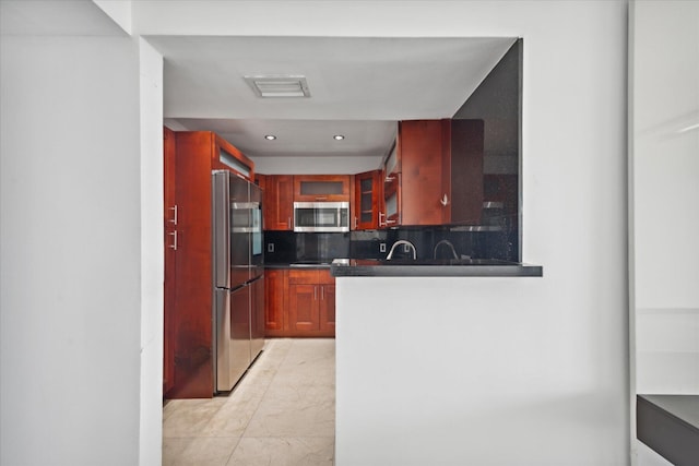 kitchen featuring appliances with stainless steel finishes, dark countertops, glass insert cabinets, and decorative backsplash