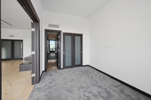 unfurnished room with light colored carpet, french doors, visible vents, and baseboards