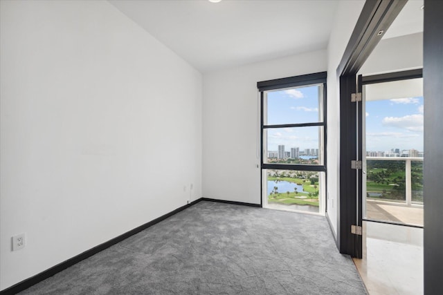 carpeted empty room with a view of city, lofted ceiling, and baseboards