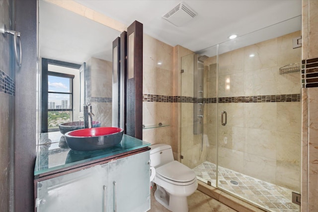 full bath featuring visible vents, toilet, vanity, a shower stall, and tile walls