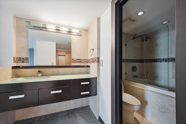 bathroom featuring tasteful backsplash, visible vents, toilet, combined bath / shower with glass door, and vanity