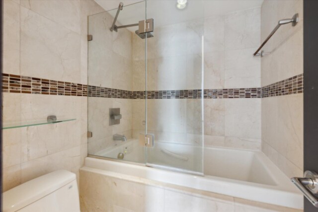 bathroom featuring tiled shower / bath, tile walls, and toilet