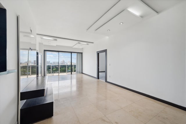 empty room with light tile patterned floors, a view of city, and baseboards