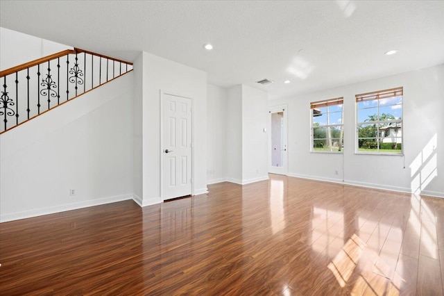 unfurnished living room featuring dark hardwood / wood-style flooring and a textured ceiling