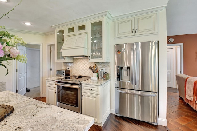 kitchen with light stone countertops, dark wood-type flooring, premium range hood, crown molding, and appliances with stainless steel finishes