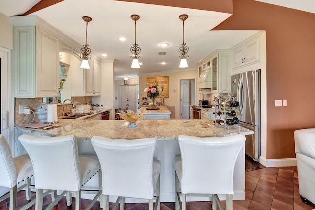 kitchen with pendant lighting, stainless steel appliances, a kitchen breakfast bar, and sink