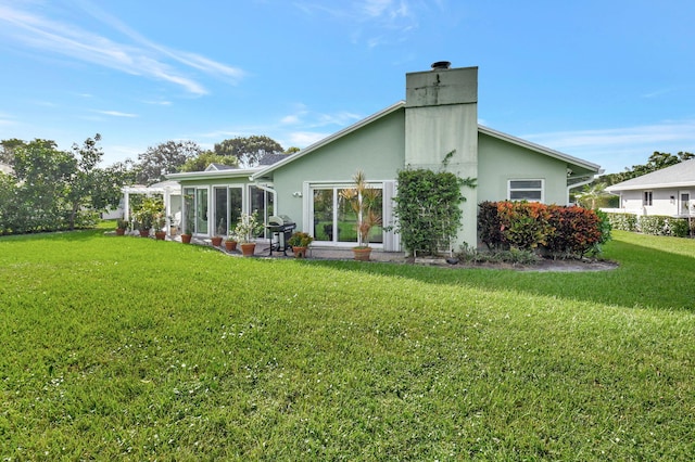 back of property featuring a lawn and a sunroom