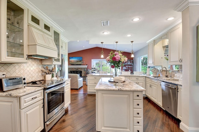 kitchen with pendant lighting, lofted ceiling, a center island, dark wood-type flooring, and stainless steel appliances