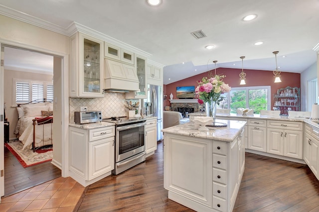 kitchen with a center island, premium range hood, decorative light fixtures, vaulted ceiling, and appliances with stainless steel finishes