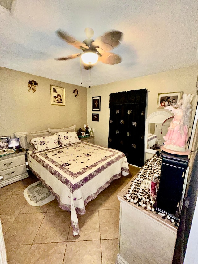 tiled bedroom featuring ceiling fan and a textured ceiling